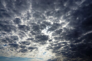 Naklejka na ściany i meble Bedeckte Himmellandschaft mit dramatischem grauen Wolkengebilde bei Sonne am Mittag im Sommer