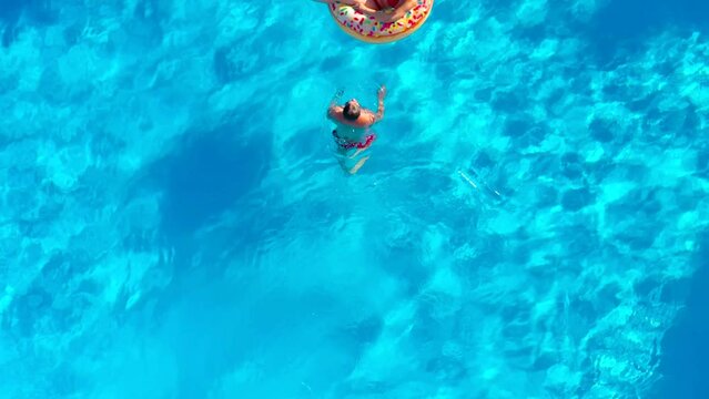 Aerial View Of A Couple Having Fun In The Pool, The Man Dives And The Woman Lies On A Donut