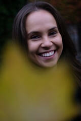 Autumn maple leaf near the smiling face of a girl