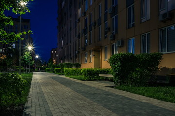 Night park paths and colored houses at summer night. Night paths, benches and lanterns in a beautiful residential complex. Night summer park with lanterns and benches. Kyiv. Ukraine