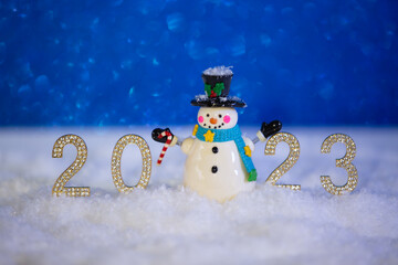 Happy snowman standing in winter sparkling christmas landscape with golden numbers 2023. . Merry...