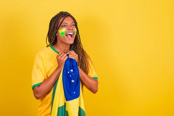Fotobehang black woman young brazilian soccer fan. holding brazil flag, anxious, watching the match. © StockImageBrasil