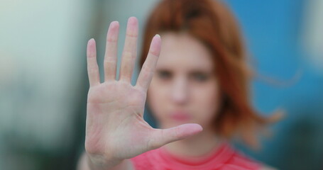 Assertive woman making stop gesture. Strong redhead lady showing hold sign