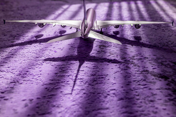 creative effect with sun light beam, airplane aircraft toy on purple violet background with lines,...