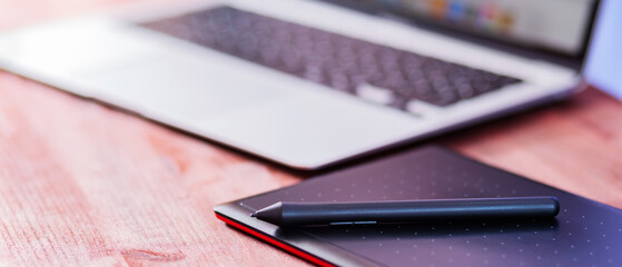 Graphic designer's workplace. Laptop and graphics tablet on a wooden table. Freelance work concept