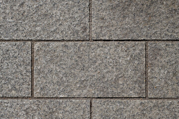 Rectangular gray cubes, equal sizes, straight, cut stones, edges on top, structure of split cubes, gaps between cubes with dark sand