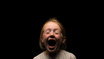Young Caucasian girl with an open mouth screaming expression.