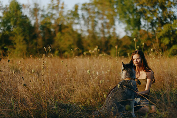 Woman sitting in field with dachshund dog smiling while spending time outdoors with dog friend