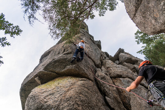 Climber climbing mountain and partner insuring below