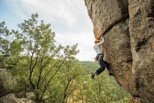Climber in equipment climbing mountain helping with hand and leg