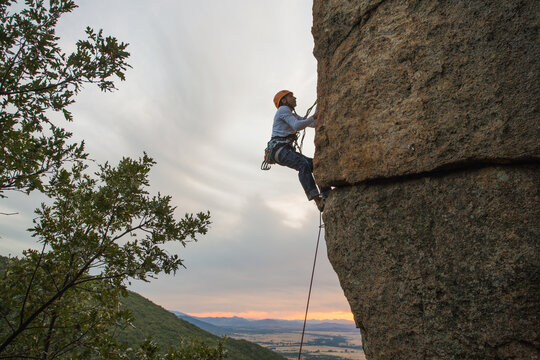 Climber in equipment climbing mountain helping with hand and leg
