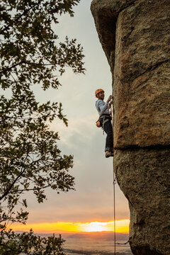 Climber in equipment climbing mountain helping with hand and leg