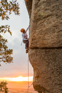 Climber in equipment climbing mountain helping with hand and leg