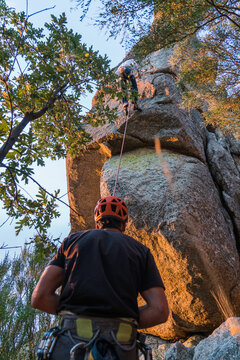 Climber climbing mountain and partner insuring below