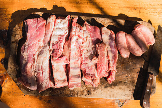 Raw meat pieces and sausages on cutting board