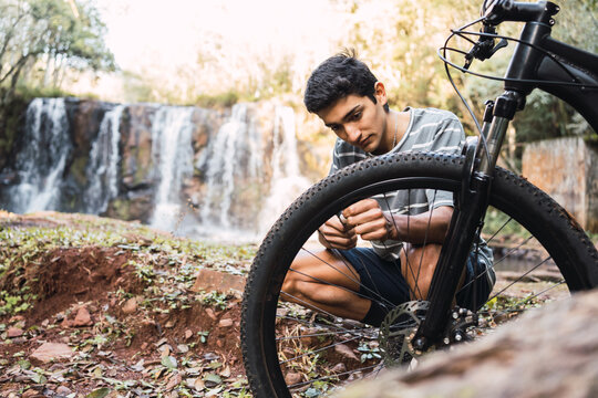 Man repairing detail of bicycle in woodland