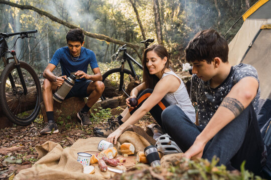 Multiracial hikers having picnic with bread and sausage
