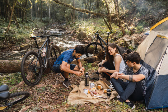 Multiracial hikers having picnic with bread and sausage