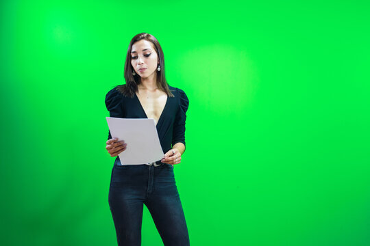 Woman with paper standing near chromakey screen