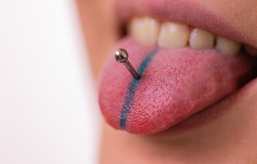 Close up portrait of young Caucasian woman sticking out pierced tongue.