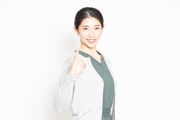 白背景の前でOKのジェスチャーをする女性