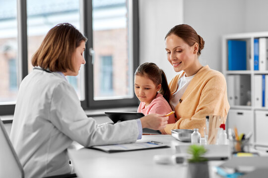 Medicine, Healthcare And Pediatry Concept - Mother With Little Daughter And Doctor Showing Tablet Pc Computer At Clinic