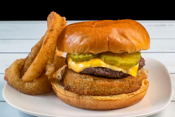 cheese burger resting on onion rings and top with pickle