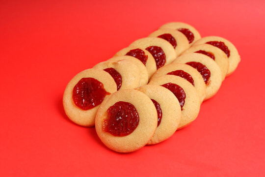 Row of round sweet cookies with quince jam center in perspective on red background
