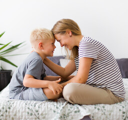 lovely emotional scene with happy mother and son in bedroom