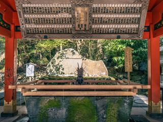 fountain with a wooden structure at the entrance of a japanese shinto shrine for purification