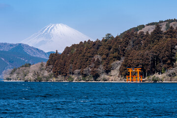 view of Mount Fuji and the vermilion torii gate of a shinto shrine from the shore of lake Ashinoko in Hakone