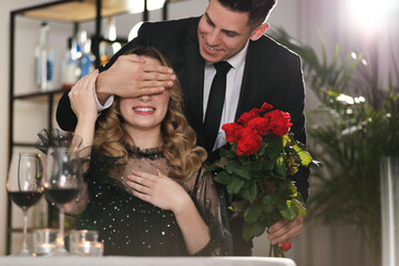 Man presenting roses to his beloved woman in restaurant at Valentine's day dinner