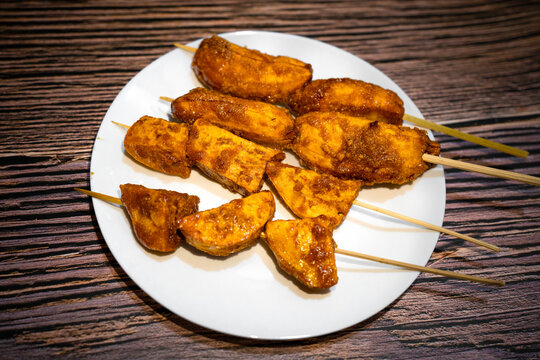 Caramelized banana and kamote que in a stick on white plate