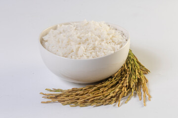 Cooked rice in a bowl and ears of rice on a white background