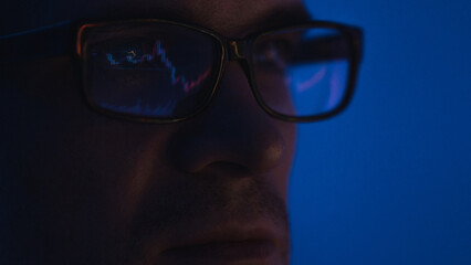 pulse of the market, a male trader with glasses sits in front of the monitor and looks at the chart of the market price of stocks or currencies, the securities market or the crypto exchange