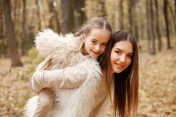 Mother and her daughter playing and having fun in autumn forest