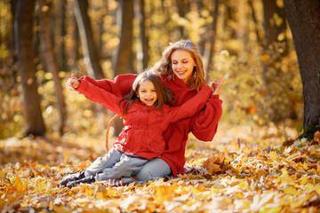 Mother and daughter sitting on a blanket in autumn forest
