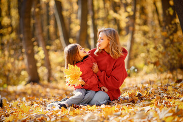 Mother and daughter sitting on a blanket in autumn forest