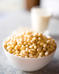 Soy beans in white ceramic bowl on platemat. Soaked japanese soy beans with a cup of soy milk