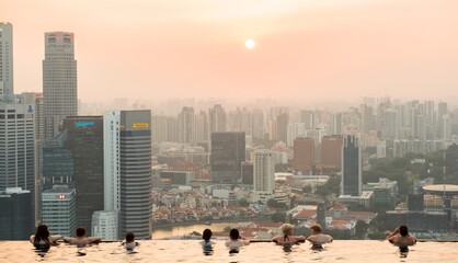 An afternoon at the infinity pool in singapore with sun setting in background over the buildings city skyline