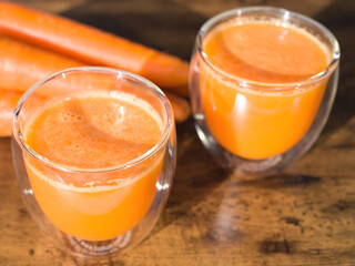 Organic carrot juice in glass on dark wooden background