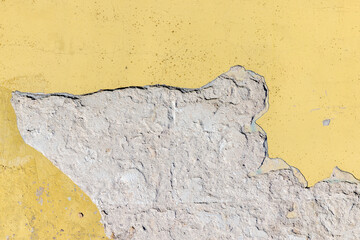 Damaged yellow plaster of a concrete wall