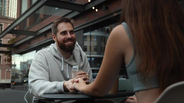 Bearded man smiling at woman during date outdoors in coffee shop