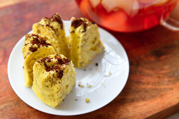 slices of homemade cake on a plate and glass teapot with stewed fruits - apples, plums and strawberries on a wooden background, concept of fresh fruits and healthy food