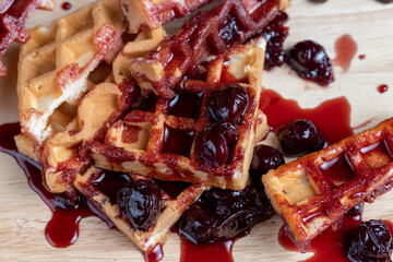 soft waffles with red cherry jam on a serving board