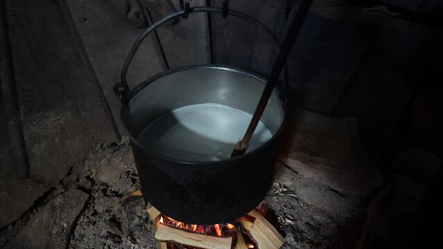 Making organic sheep cheese in wooden mountain Carpathian cheese factory with a boiling smoked cauldron with milk on open fire, Western Ukraine, Europe