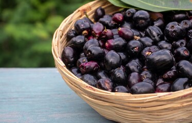 Closeup of Jamun or Syzygium Cumini in a Bamboo Basket on Wooden Background with Copy Space, Also Known as Java Plum, Malabar Plum, Black Plum or Jambolan