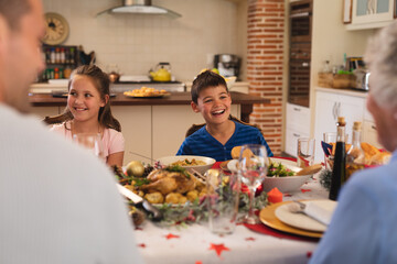 Multi generation caucasian family sitting at table for dinner together and smiling