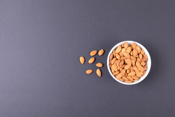 Directly above shot of bowl full with almonds over black background along copy space