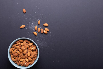 Directly above shot of almonds in bowl with salt on black background